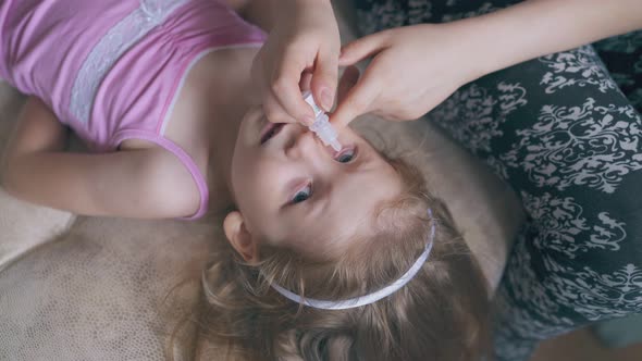 Mommy Drops Girl Eyes with New Cure on Soft Beige Bed