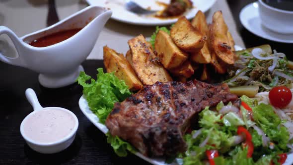 Steak on Ribs with Potatoes and Salad on a Table in a Georgian Restaurant