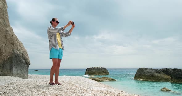 Tourist taking pictures of beach with smartphone.