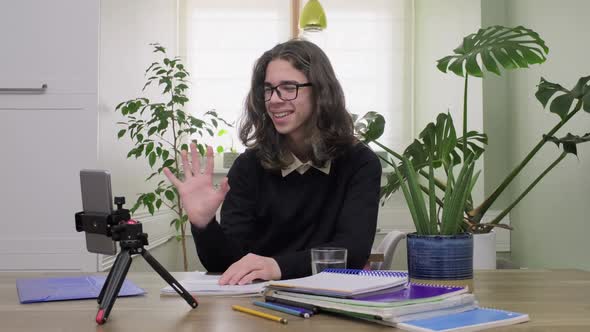 Male Teenage High School Student at Home Looking at Smartphone Camera Studying Online