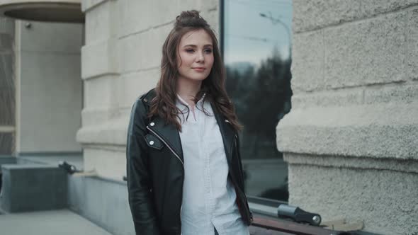 Hipster Girl Walking in the City. Portrait of a Young Woman in a Leather Jacket on the Street.