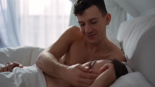 Portrait of Happy Loving Gay Man Caressing Face of Sleeping Boyfriend at Home in the Morning