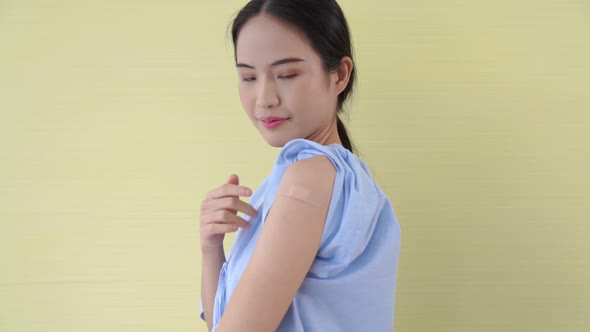 Young Asian Woman Showing COVID19 Vaccine Bandage Merrily