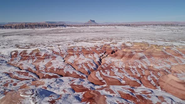 Aerial view of eroded cracks in the red desert of Utah with snow