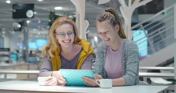 Good Looking Mother Watching Funny Video with Teenage Daughter Using Tablet PC. Family Overjoyed