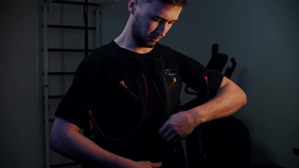 A Man Fastens a Vest with EMS Equipment and Looks Into the Camera