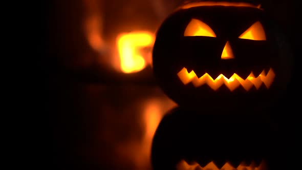 Creepy halloween pumpkin near a fireplace. Fire on the background.