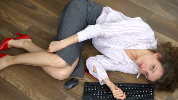 Tired Young Female Office Manager is Lying on the Floor with Keyboard Mouse and Smartphone Lay Flat