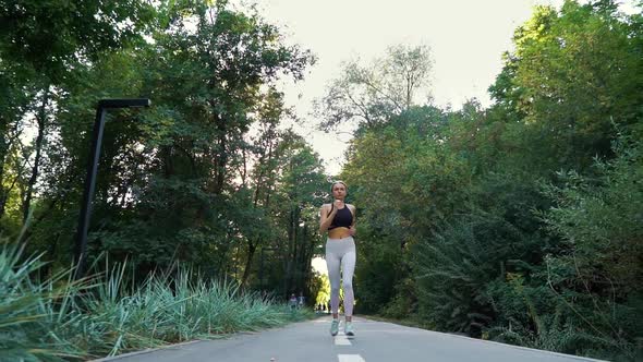 Woman in Sexy Sportswear Jogging in Park