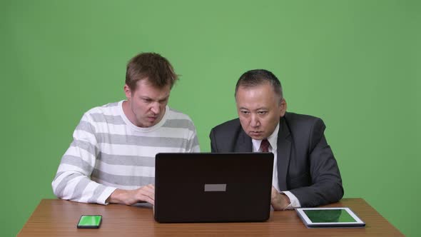 Mature Japanese Businessman and Young Scandinavian Businessman Working Together