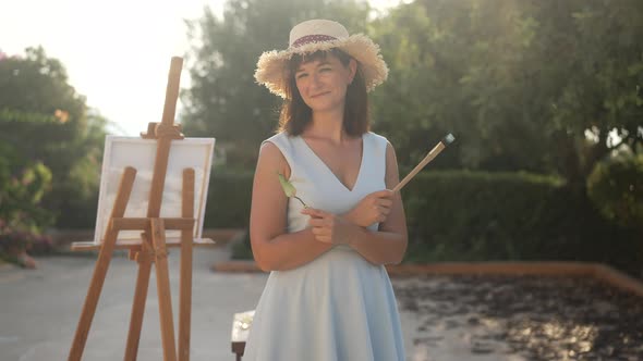 Happy Charming Female Painter Standing in Sunrays Crossing Hands with Painting Knife and Brush / Videohive, Stock footage, People