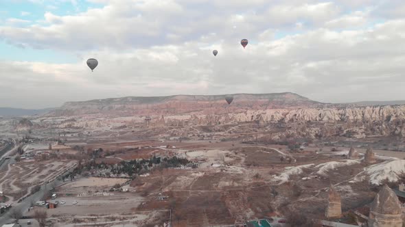 Hot air balloons fly over Goreme Valley in Cappadocia, Turkey - Ascending Wide Aerial 