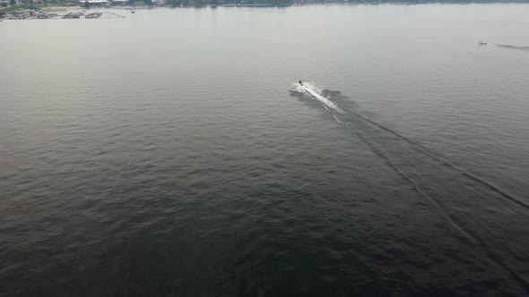 Crane drone shot of a jet skier driving towards the marina on Lake Payette in McCall, Idaho. This 4K