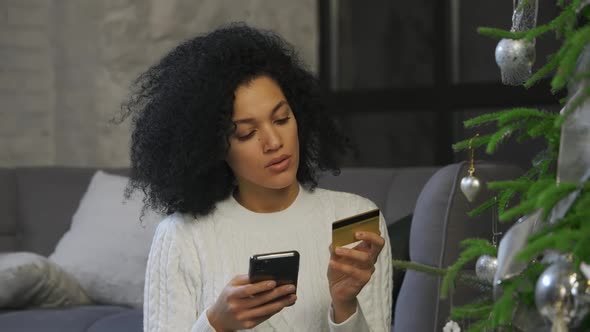 Portrait of Happy African American Woman Making Online Purchase Using Her Smartphone and Credit Card