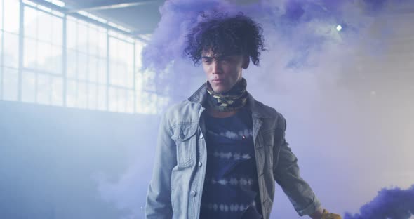 Mixed race man holding blue flare walking through empty building