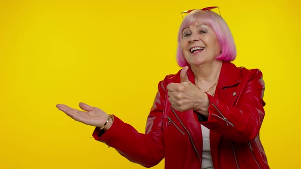 Senior Old Granny Woman Showing Thumbs Up and Pointing at Left on Blank Space Advertisement Logo