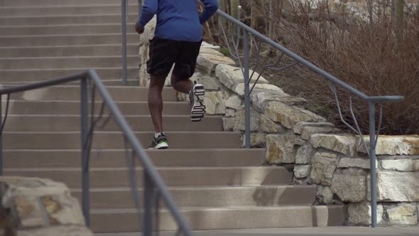 A young man running stairs in the mountains.