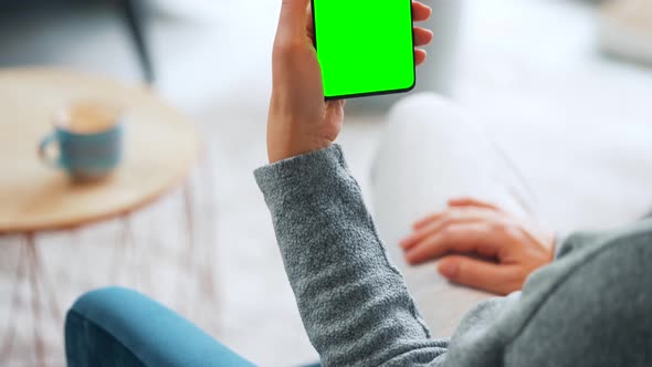 Woman at Home Using Smartphone with Green Mockup Screen in Vertical Mode