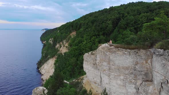 Young Shirtless Man Meditating on a Cliff Around the Forest and River in Early Morning