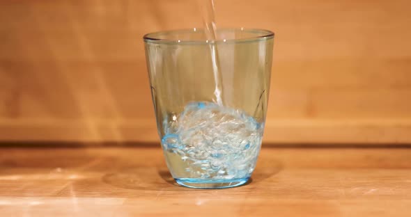 Healthy Eating Diet and Drinks Concept  Water Pouring Into Glass on Wooden Table