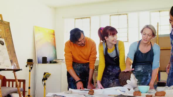 Drawing teacher assisting artists on ceramic sculpture