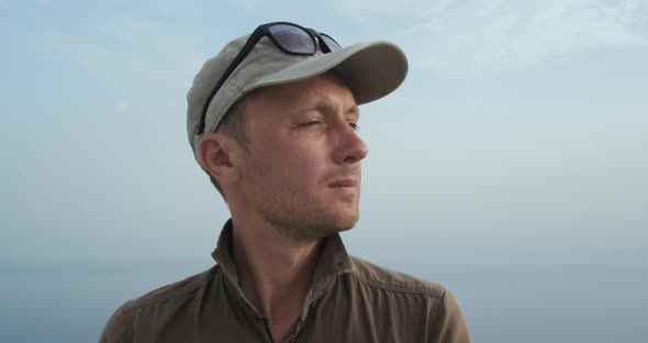 Portrait Pensive Man Against Background of Blue Sky and Sea Closeup