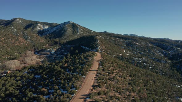 Aerial moving down mountain desert road with car parked on scenic overlook