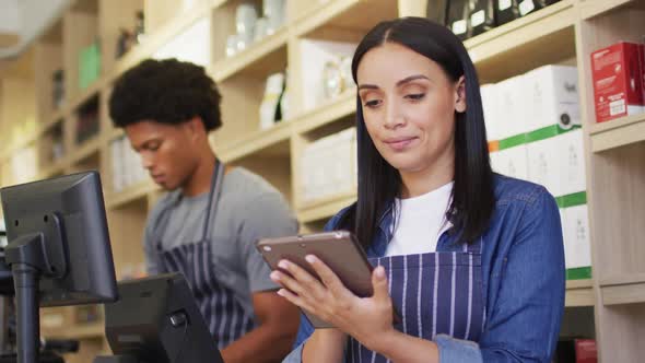 Animation of thoughtful biracial waitress using tablet in coffee shop