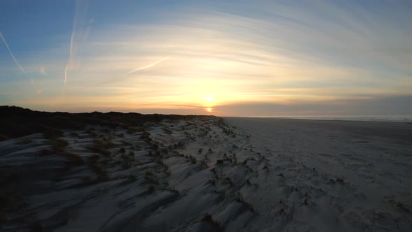 Aerial, drone shot over dunes, at a beach, towards the sunset, on Langeoog island