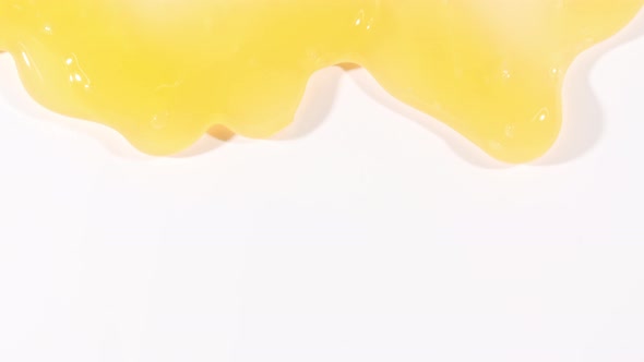 Yellow Cosmetic Gel Fluid Flowing Down on a White Surface