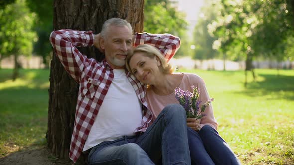 Romantic Date of Two Retired People, Man Hugging Wife With Flower Bouquet