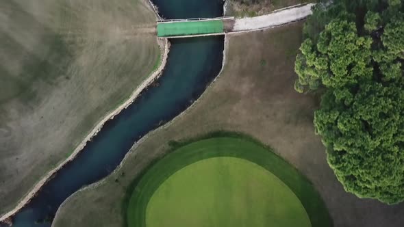 Top down view of vibrant green golf course field in aerial motion shot