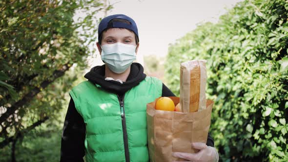 Delivery Worker Wearing Face Mask in Uniform Holding Bag of Food Groceries