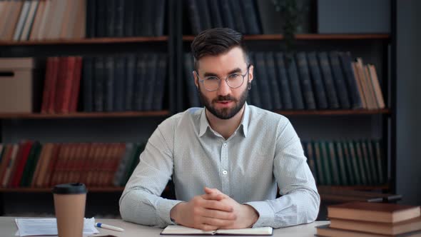 Hispanic Male Blogger Shooting Video Talking Explaining Business Education News at Library Desk