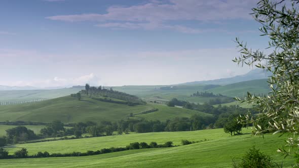 Classical Tuscany View. Green Hills Covered with Grass, Trees and Single Villas Against Blue Skies