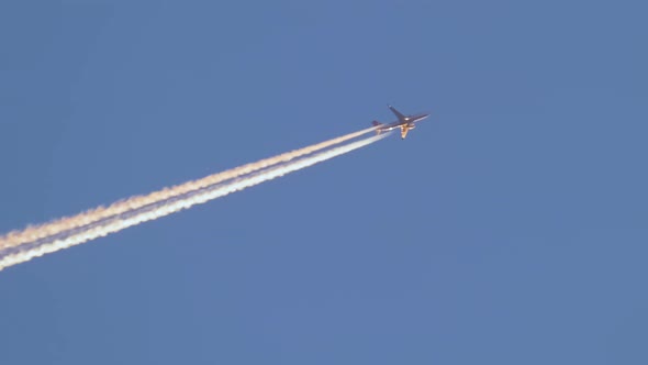 Distant Passenger Jet Plane Flying on High Altitude on Clear Blue Sky Leaving White Smoke Trace of