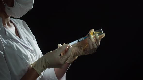 Doctor Filling Syringe with Solution on Black Background