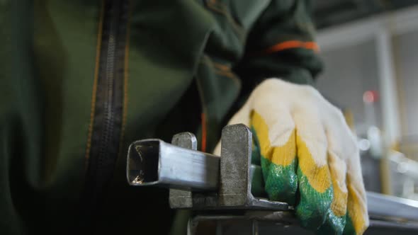 Worker in Protective Uniform Puts and Fixes Long Metal Part