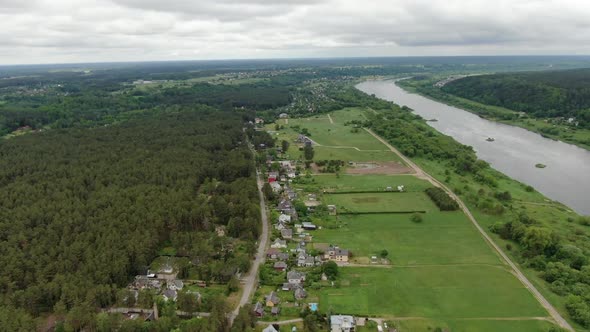 Majestic Lithuania landscape on cloudy day with river and forest, flying view over small town