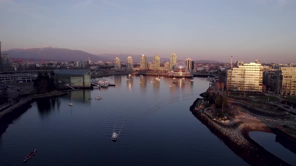 Aerial forward over False Creek at sunset toward Science World building, Vancouver in Canada