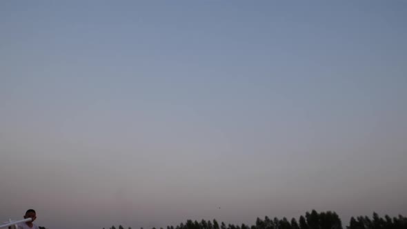 Boy playing wood airplane in the hands of running on a field at sunset