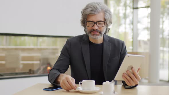 Mature Business Man Working On Tablet In Restaurant