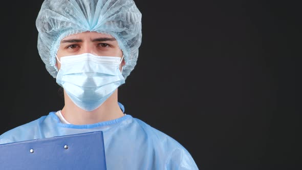 Serious Man in a Blue Medical Coat and Medical Mask Looking at Camera