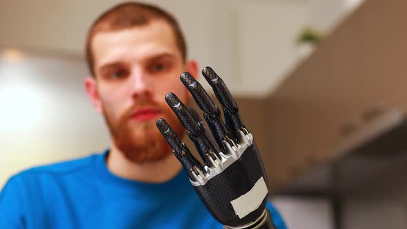 Young Man with Robotics Mechanical Modern Bionic Hand in Home