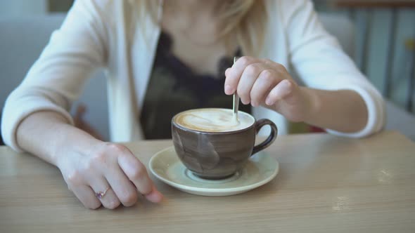 the Girl's Hands Stir the Sugar in a Cup of Latte Close Up