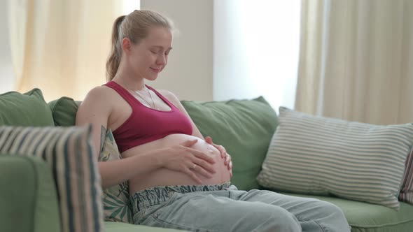 Pregnant Woman Stokes Her Big Belly While Sitting on Sofa