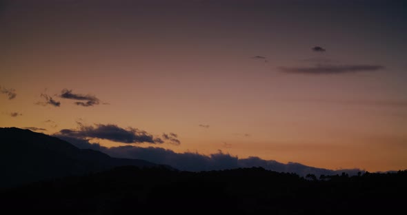 Cloudscape Timelapse at Sunset Clouds Arising Over Mountain Silhouette