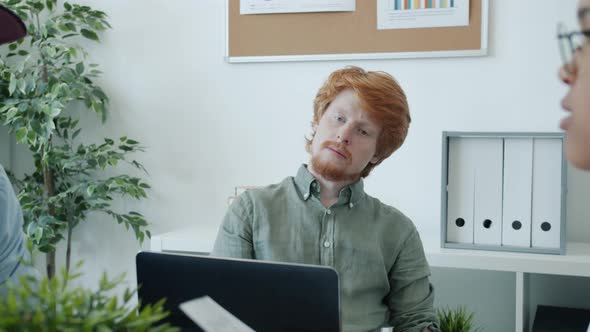 Attractive Young Businessman Flying Paper Planes Sitting at Boring Business Meeting in Office