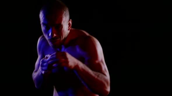 Aggressive Fighter is Punching Air to Camera in Darkness Medium Portrait of Boxer