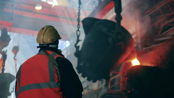 Steel Worker is Looking at the Melting Pot with Melted Metal